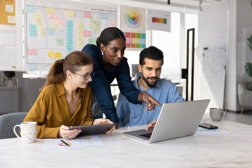 Three people working on a laptop